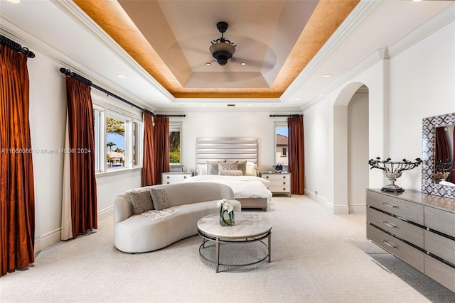 carpeted bedroom with ceiling fan, a tray ceiling, and ornamental molding