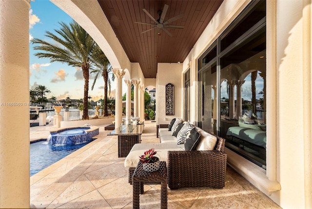 patio terrace at dusk featuring pool water feature, ceiling fan, outdoor lounge area, and a pool with hot tub