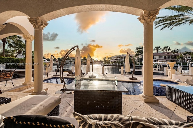 patio terrace at dusk featuring a water view