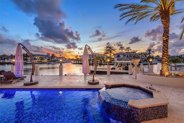 pool at dusk featuring a water view