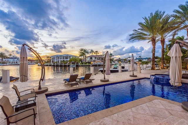 pool at dusk with a water view, an in ground hot tub, and a patio area