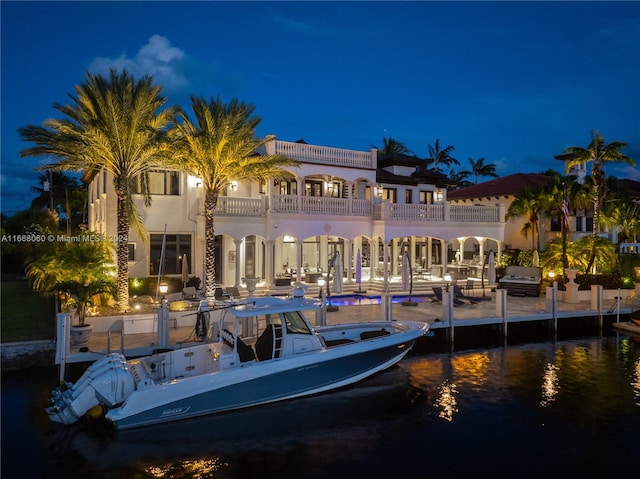 back house at twilight featuring a water view and a balcony