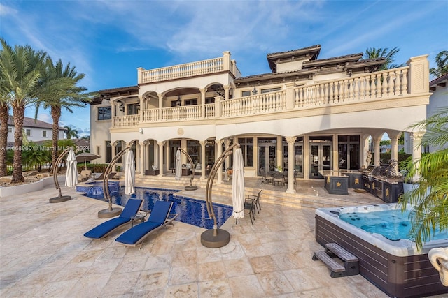 rear view of house featuring a balcony, a hot tub, and a patio area