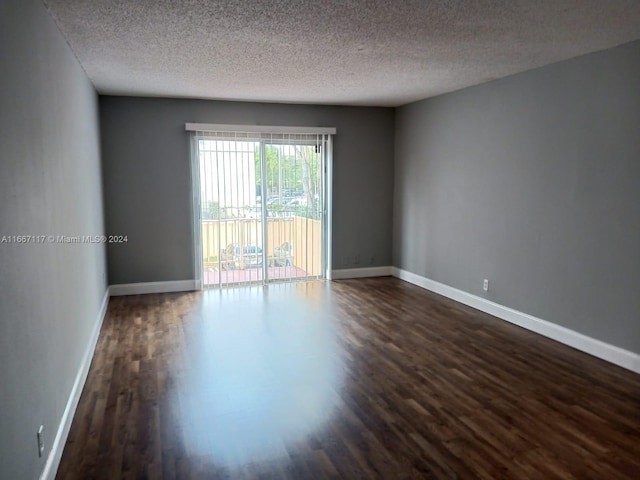 empty room with a textured ceiling and dark hardwood / wood-style flooring