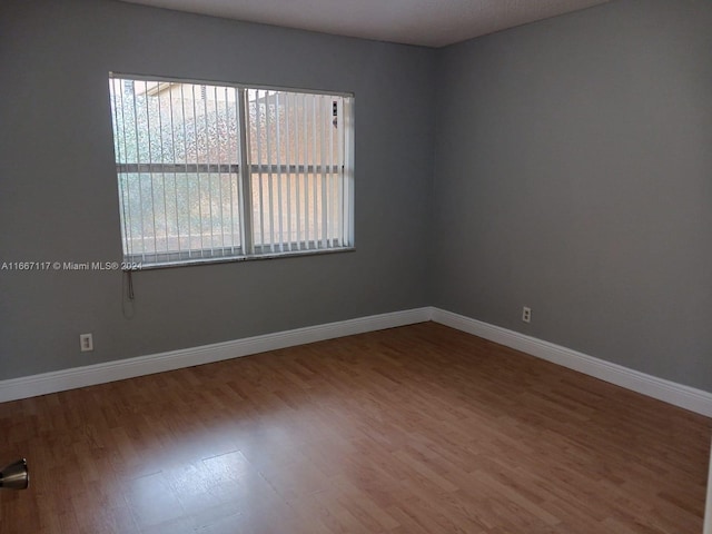 empty room with plenty of natural light and hardwood / wood-style floors