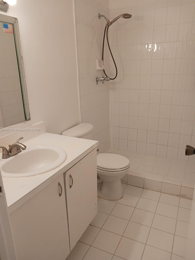 bathroom featuring a tile shower, vanity, toilet, and tile patterned floors