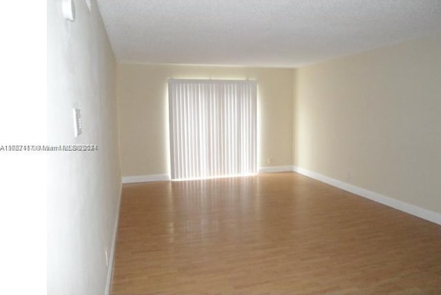 empty room with a textured ceiling and light hardwood / wood-style flooring