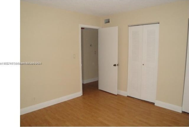 unfurnished bedroom with a closet and hardwood / wood-style floors