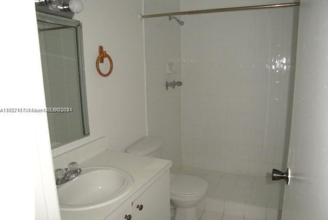 bathroom featuring tiled shower, vanity, toilet, and tile patterned floors