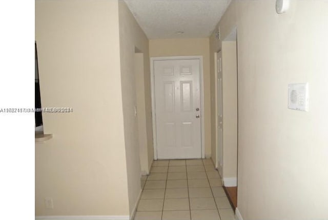 corridor with a textured ceiling and light tile patterned flooring