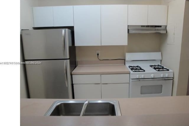 kitchen featuring white cabinetry, white gas stove, and stainless steel refrigerator