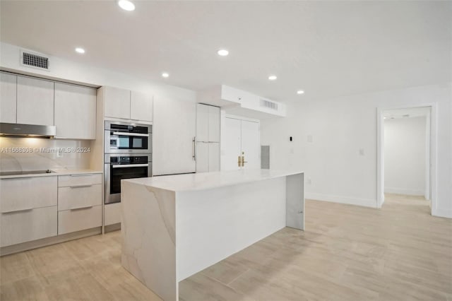 kitchen with a center island, light hardwood / wood-style flooring, double oven, tasteful backsplash, and stovetop