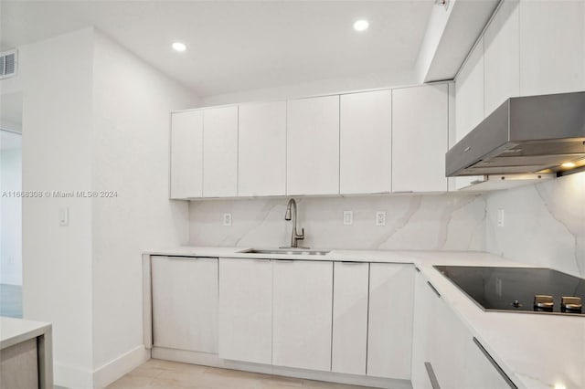 kitchen featuring white cabinets, wall chimney range hood, sink, decorative backsplash, and black electric cooktop