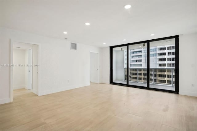 unfurnished room featuring floor to ceiling windows and light hardwood / wood-style floors