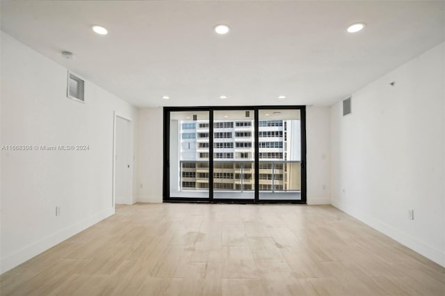 spare room featuring light hardwood / wood-style floors and a wall of windows