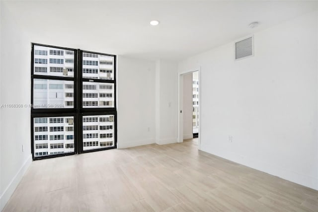 unfurnished room with light hardwood / wood-style floors and expansive windows