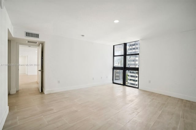 unfurnished room with light wood-type flooring and a wall of windows