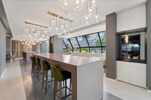 kitchen with a breakfast bar, white cabinetry, a center island, and pendant lighting