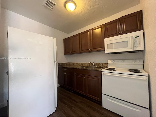 kitchen with visible vents, dark brown cabinets, white appliances, dark wood-type flooring, and a sink