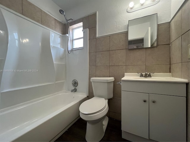 full bath featuring tile walls, shower / bathing tub combination, vanity, and toilet