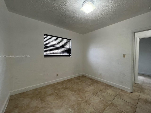 unfurnished room featuring baseboards and a textured ceiling