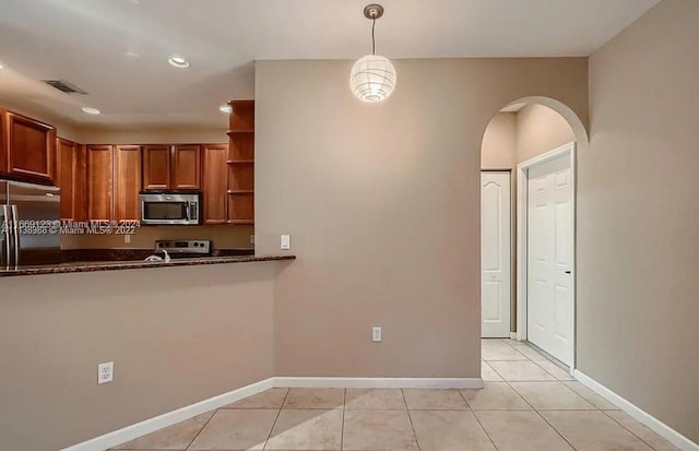 kitchen featuring dark stone countertops, pendant lighting, light tile patterned flooring, and appliances with stainless steel finishes