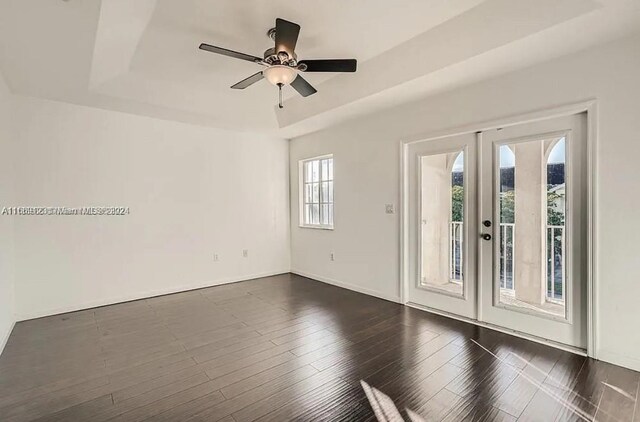 interior space featuring ceiling fan, a raised ceiling, plenty of natural light, and dark hardwood / wood-style floors