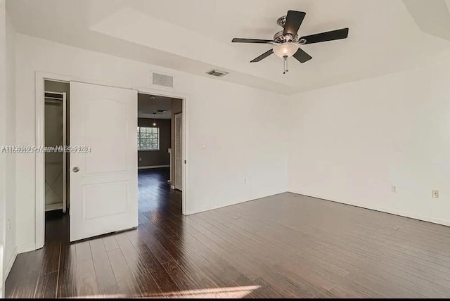 empty room with ceiling fan and dark hardwood / wood-style flooring