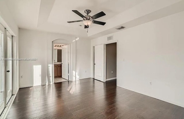 unfurnished bedroom with ceiling fan, connected bathroom, and dark hardwood / wood-style floors