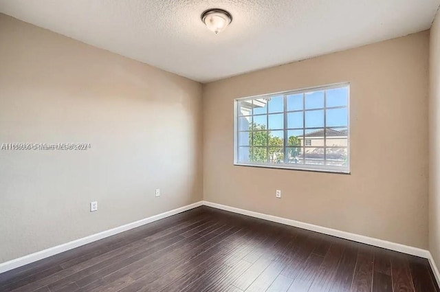 empty room featuring a textured ceiling and dark hardwood / wood-style floors