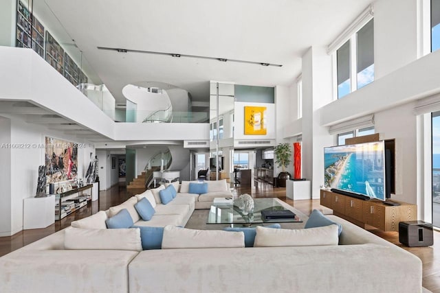 living room with a healthy amount of sunlight, a high ceiling, track lighting, and hardwood / wood-style floors