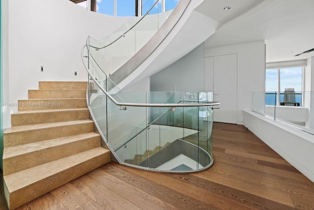 staircase with a water view and hardwood / wood-style floors