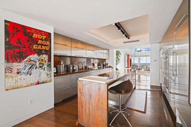 450 Alton Rd Unit Ph2, Miami Beach, FL 33139 - indoor wet bar featuring a raised ceiling, dark wood-style flooring, baseboards, and rail lighting
