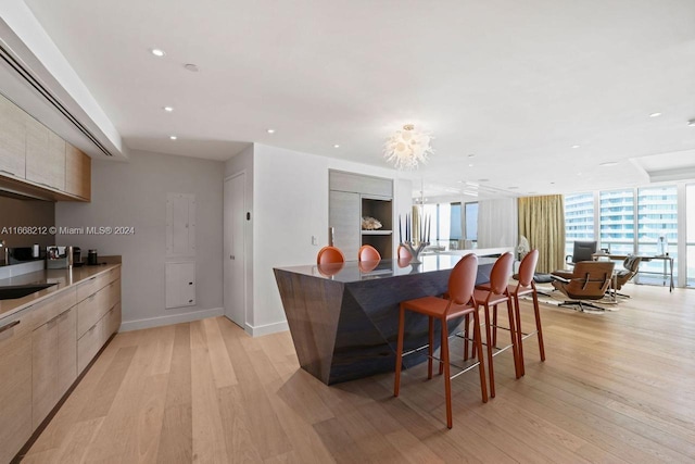 kitchen featuring light brown cabinetry, a kitchen bar, floor to ceiling windows, and light hardwood / wood-style floors