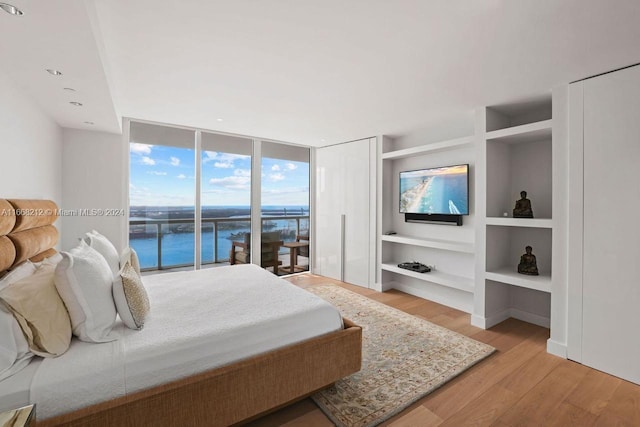 bedroom with access to exterior, a wall of windows, and light hardwood / wood-style floors