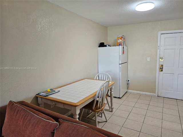 dining space with a textured ceiling and light tile patterned flooring