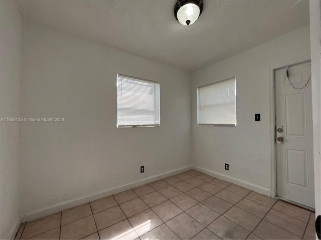 empty room featuring light tile patterned floors and baseboards