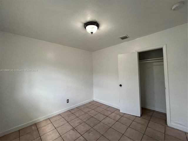 unfurnished bedroom featuring baseboards, visible vents, light tile patterned floors, and a closet
