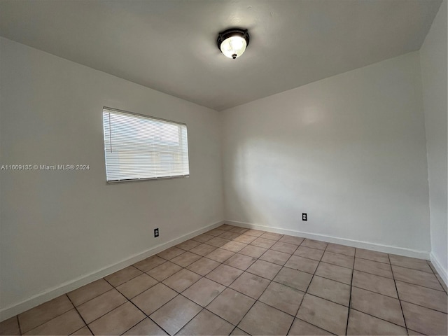 spare room featuring baseboards and light tile patterned flooring