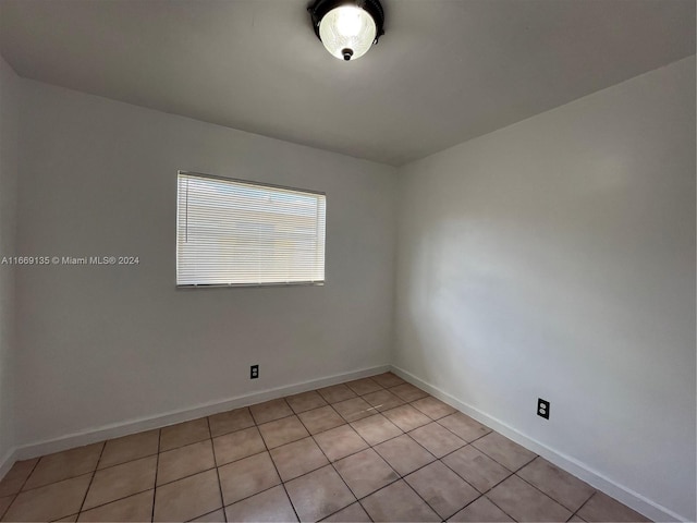 empty room featuring baseboards and light tile patterned flooring