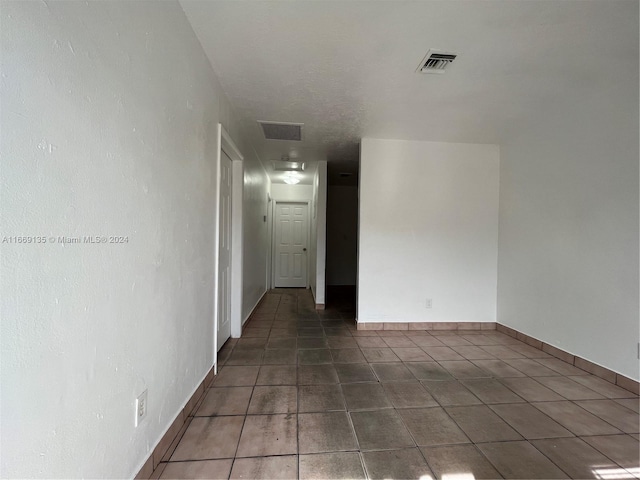 empty room featuring tile patterned floors, baseboards, and visible vents