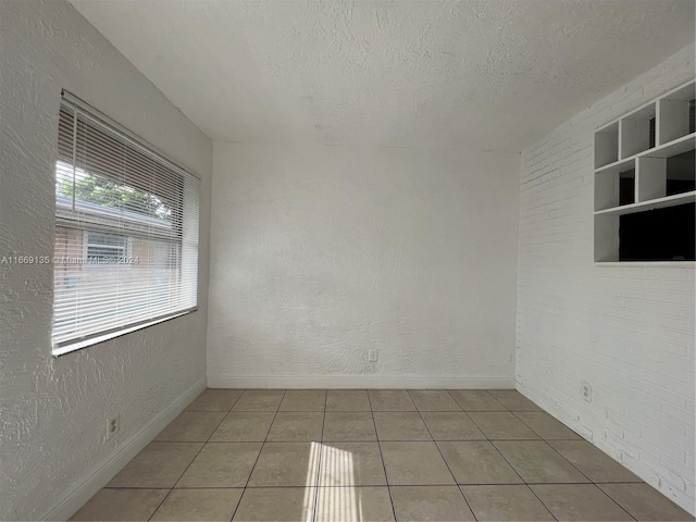 spare room featuring baseboards, tile patterned flooring, and a textured ceiling