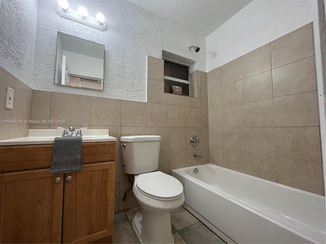 bathroom featuring toilet, a textured wall, tile walls, and vanity