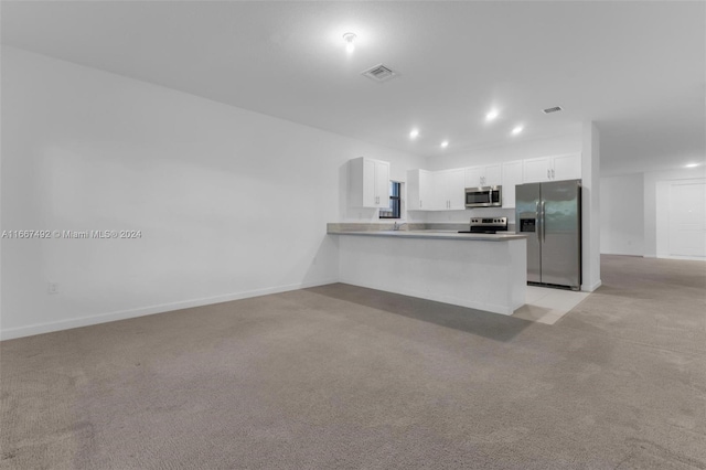 kitchen with kitchen peninsula, white cabinets, light colored carpet, and appliances with stainless steel finishes