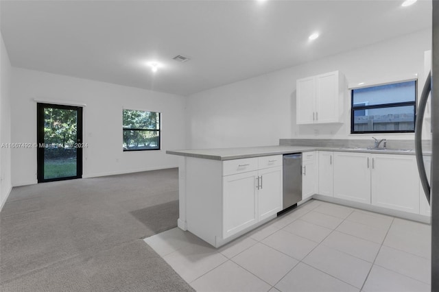 kitchen with dishwasher, sink, kitchen peninsula, light colored carpet, and white cabinetry