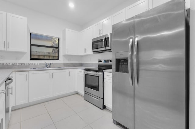 kitchen with white cabinets, light tile patterned flooring, sink, and stainless steel appliances