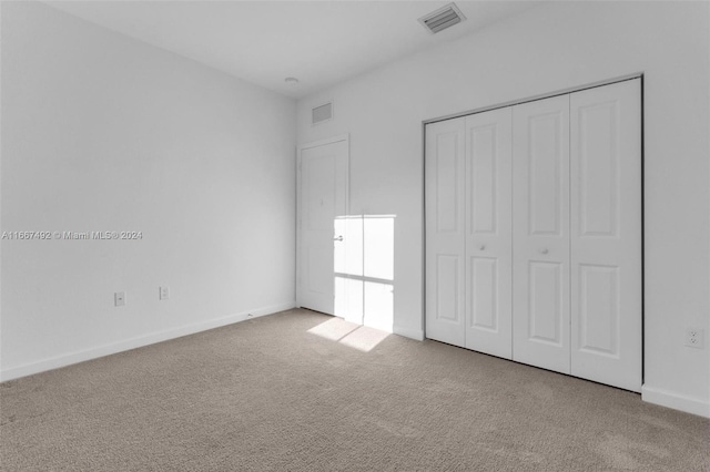 unfurnished bedroom with light carpet and a closet