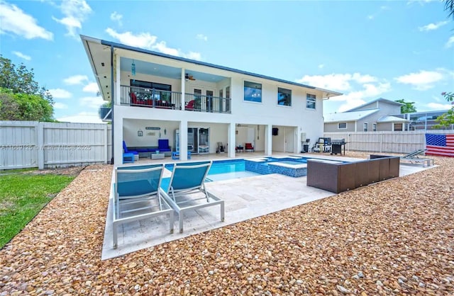 rear view of house with ceiling fan, a balcony, a pool with hot tub, and a patio area