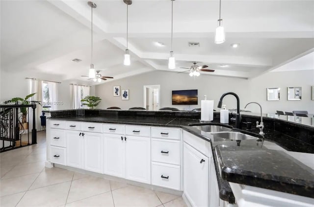 kitchen with dark stone counters, decorative light fixtures, sink, and white cabinets