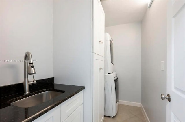 laundry area with stacked washer / dryer, sink, and light tile patterned floors